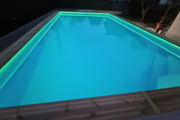 Piscina in legno autoportante installata in giardino, con struttura rinforzata, platea in cemento, rivestimento interno azzurro e illuminazione LED perimetrale. Le foto mostrano le diverse fasi del montaggio: dallo scavo iniziale alla realizzazione della base, fino all’assemblaggio delle pareti in legno e al risultato finale con acqua e luci serali. Una soluzione elegante e robusta per chi desidera una piscina fuori terra in legno di grandi dimensioni, perfettamente integrata nello spazio esterno.