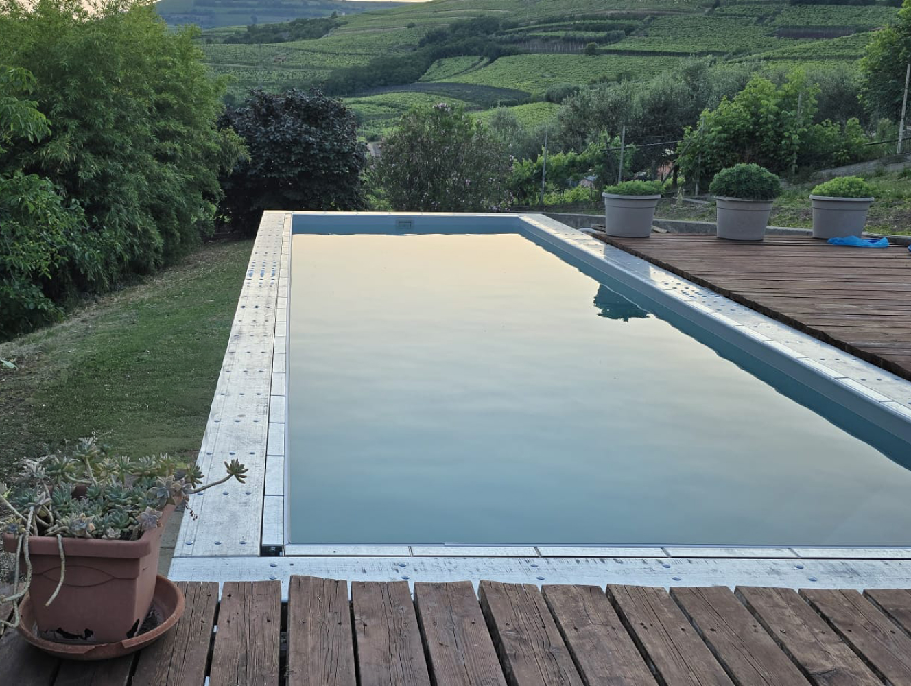 Piscina fuori terra autoportante Astrea 8,65x3,05 m con deck in legno e vista panoramica sulle colline
