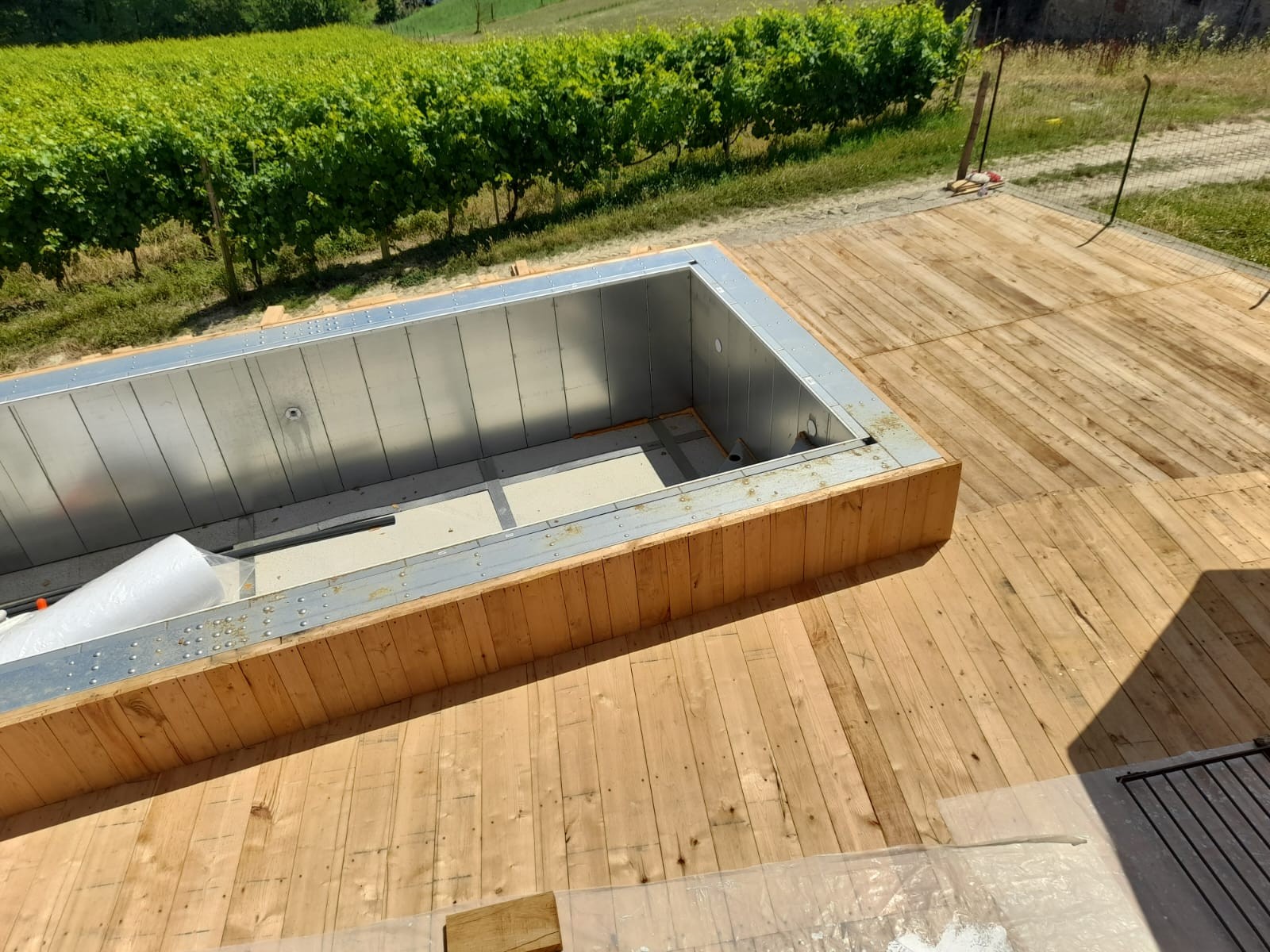 Piscina autoportante ASTREA con deck in legno, installazione su terrazza panoramica vicino ai vigneti