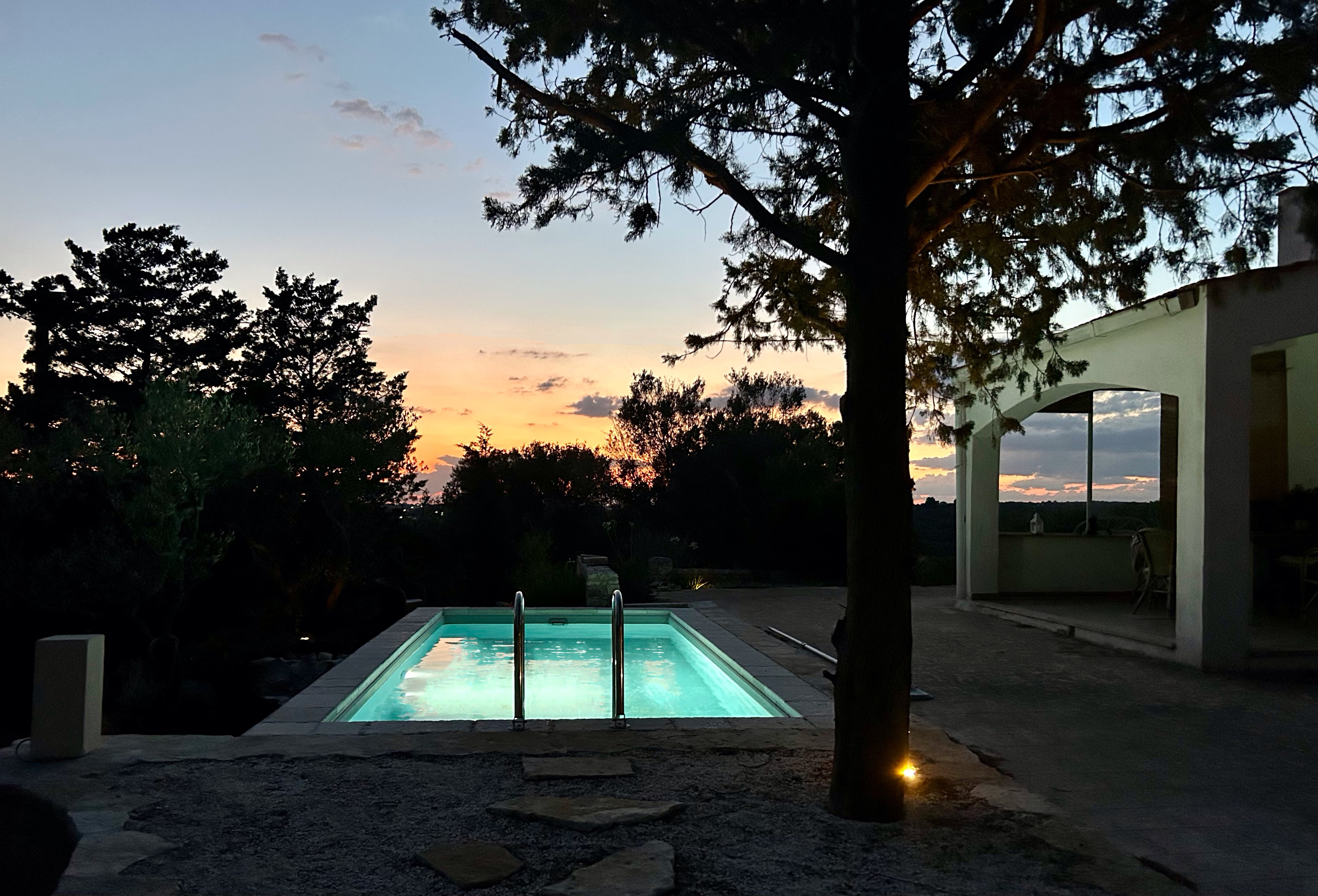 Piscina fuori terra rettangolare Astrea illuminata al tramonto con luce interna e contesto naturale