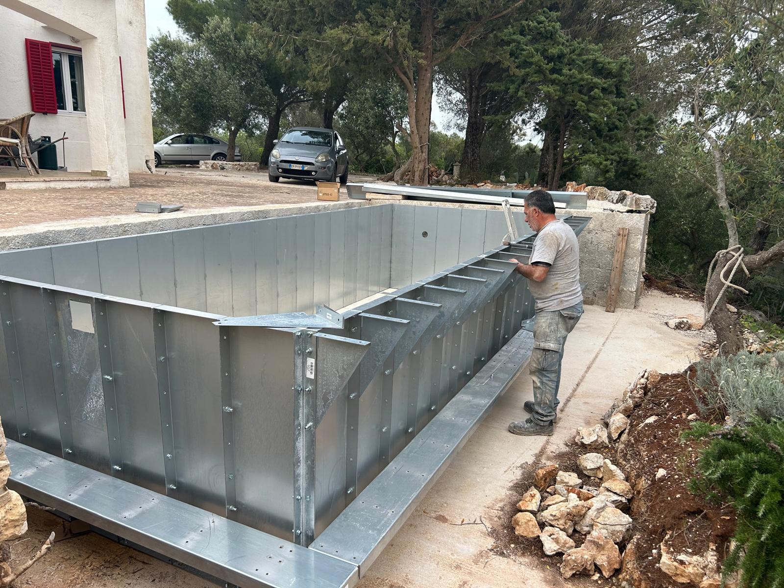 Operai al lavoro per montare la piscina autoportante ASTREA 6 metri su pavimento in cemento