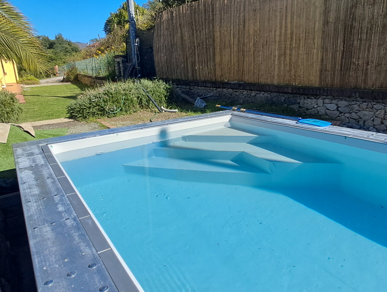Piscina in acciaio rettangolare con scala d’angolo vista giardino